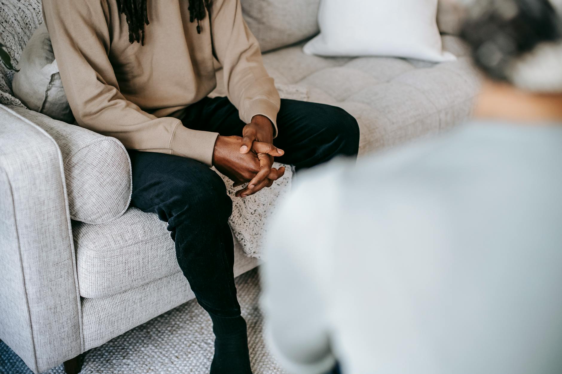 A person with clasped hands sitting in a therapy session, reflecting the thoughtful self-awareness that helps identify why ADHD treatment needs adjustment